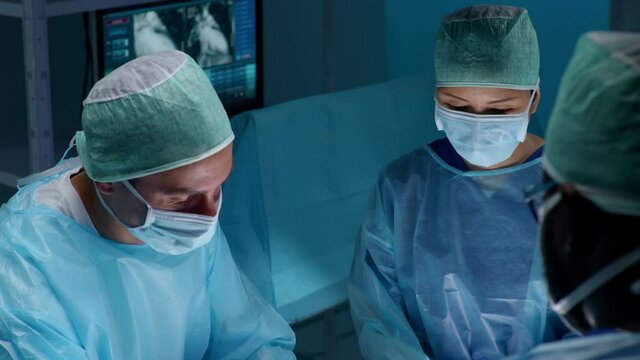 Team of professional medical surgeons performs the surgical operation in a modern hospital. Doctors are working to save the patient. Medicine, health, cardiology and transplantation concept.