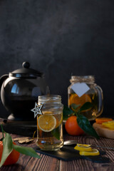 Teapot with hot citrus tea from oranges, lemons and limes, healthy drink, rustic background