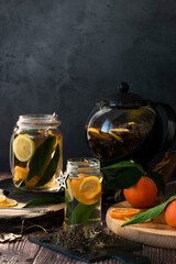 Teapot with hot citrus tea from oranges, lemons and limes, healthy drink, rustic background