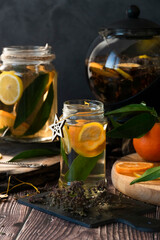 Teapot with hot citrus tea from oranges, lemons and limes, healthy drink, rustic background