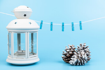 Obraz premium White lantern with candle inside and Christmas decoration on blue background. Copy space.