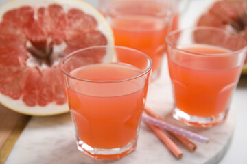 Glasses of pink pomelo juice on white table, closeup