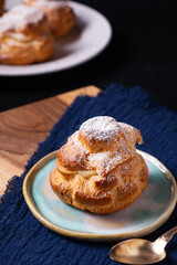 Food concept Homemade fresh baked Choux a la creme, Cream Puff, Choux Cream in white ceramic plate on black background with copy space