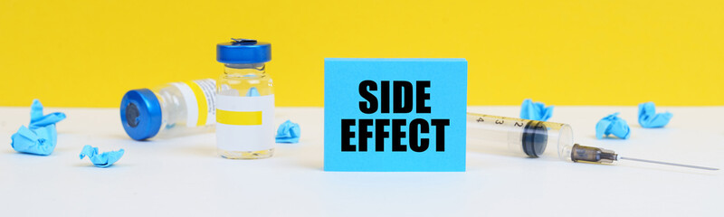 On the table is a syringe, injections and a blue sign with the inscription - SIDE EFFECT