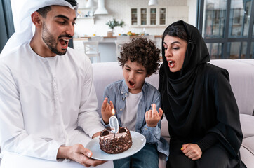 happy family spending time together at home during the Dubai national day. Arabian parents and their son wearing emirates traditional clothes