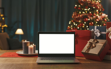 Laptop with blank screen, gifts and Christmas tree