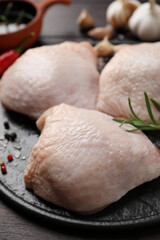 Raw chicken thighs with rosemary and spices on wooden table, closeup
