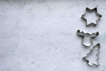 Christmas cookie cutters in star, christmas tree, deer shape on gray concrete background with copy space. Christmas frame, border, background
