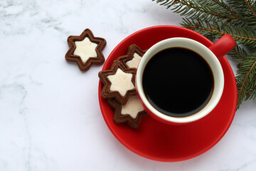 Obraz na płótnie Canvas Cup of coffee with star shaped cookies, cinnamon sticks and christmas decorations on white marble table. Christmas background. Top view, copy space. Flat lay winter holidays composition