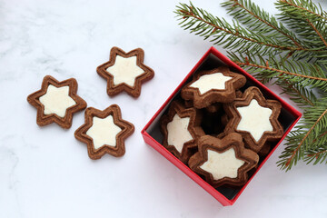 Christmas background with star shaped cookies in red gift box, fir tree branches and christmas decorations. Flat lay festive composition. Top view

