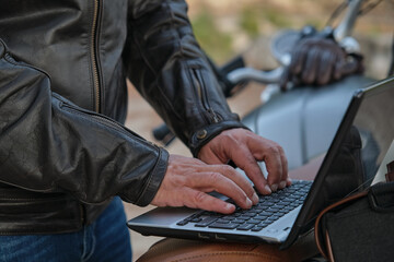 Close up of unrecognizable man using a laptop while traveling with his motorcycle.