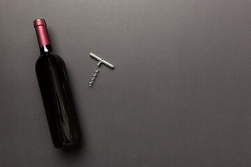 One Bottle of red wine with corkscrew on colored table. Flat lay, top view wth copy space