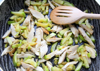Chicken meat and fresh vegetable marrow are fried in a pan. Chicken breast cooked in chunks with...