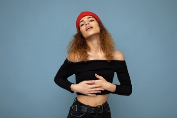 Photo of pretty beautiful attractive positive sexy cool young curly dark blonde woman standing isolated over blue background wall with copy space for text wearing everyday trendy and stylish black top