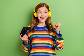 Portrait of attractive cheerful lucky girly girl playing video game having fun celebrating isolated over bright green color background