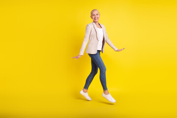 Fototapeta na wymiar Full body profile side photo of excited mature lady jumper go walk empty space isolated over yellow color background