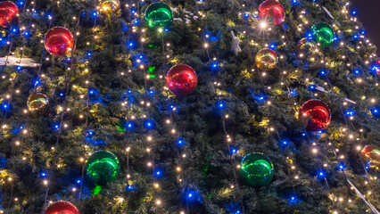 Close-up view of decorated Christmas tree. Beautiful Christmas tree decorated with shiny baubles and lights garland.