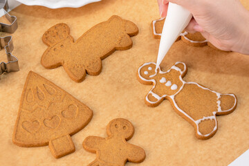Decorating Christmas gingerbread man cookie with frosting.