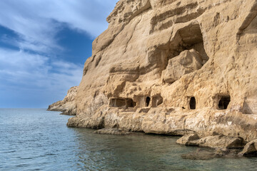 Fototapeta na wymiar Stunning neolithic era caves on the cliff of Matala beach, Southern Crete, Greece. Used as historically used as living spaces and tombs