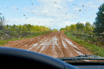 POV inside car windshield view point. View on dirty country road in nature landscape. Concept of...