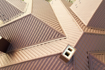 Detail of house roof structure covered with brown metal tile sheets.