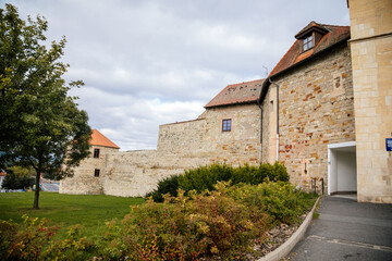 Fototapeta na wymiar Louny, Czech Republic, 19 September 2021: Zatec Gate with wall and prismatic bastions, medieval fortification complex with wooden corridor under roof in autumn day, Latin inscriptions on front facade