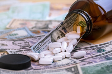The tablets are scattered from the glass packaging on the banknotes. The concept is to raise the price of medicines. Investing in pharmaceuticals.