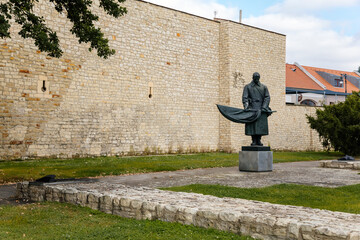 Louny, Czech Republic, 19 September 2021: Statue of Red Army man near town wall, medieval fortification complex in autumn day, monument to unknown soldier, park and green trees