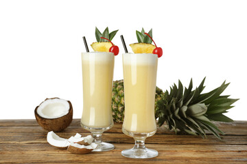 Tasty Pina Colada cocktail and ingredients on wooden table against white background
