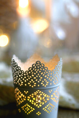 Candle holder with lit candle, reindeer and Christmas tree figurines and soft blanket. Hygge at home. Selective focus.
