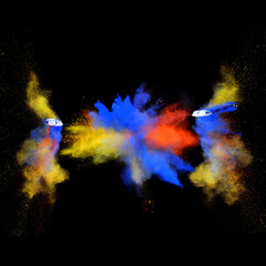 Blue and yellow bizarre forms of powder paint explode in front of a black background to give off fantastic multi colors and forms.