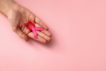 Woman holding pink ribbon on color background, top view with space for text. Breast cancer awareness concept