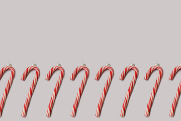 Christmas bauble decoration made of red and white candy cane on very peri purple background. Minimal flat lay concept. New Year pattern. Copy space.