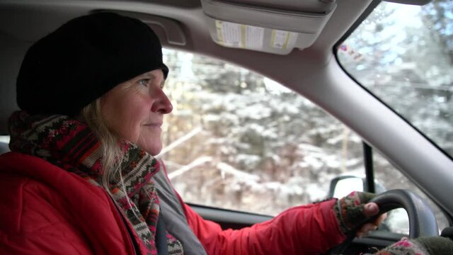 A woman driving on a snowy winter day.