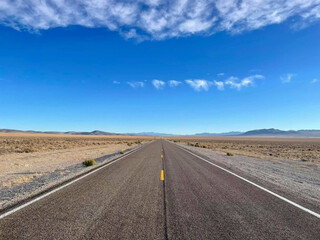 Beautiful panoramic view of a deserted and endless road through the mountains, Nevada, United States.