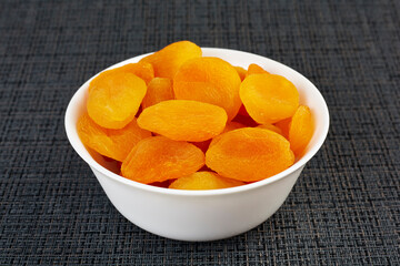 Dried apricots in a white plate on a black background. The concept of healthy eating