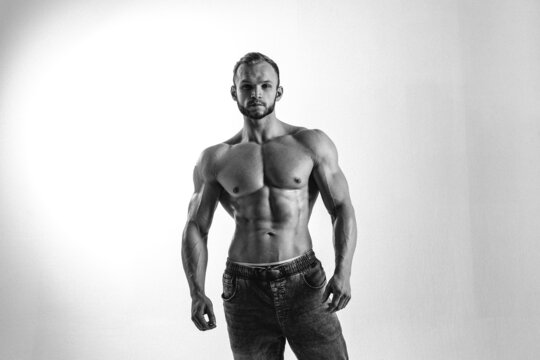 young man, brutal appearance, with a beautiful torso, bodybuilder, in the studio on a white background, BW photo