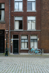 Fototapeta na wymiar A blue bicycle is standing on a Dutch street. Old classic holland street with a blue bike. Typical holland street