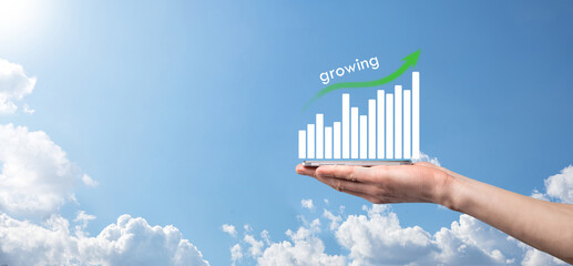 Business man holding holographic graphs and stock market statistics gain profits. Concept of growth planning and business strategy. Display of good economy form digital screen.