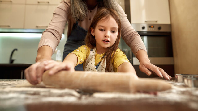 Girl roll out dough with rolling pin with grandma
