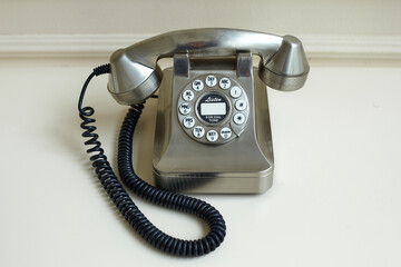 old metal-colored disk phone on a light background