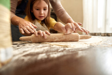 Caucasian little girl roll out dough senior woman