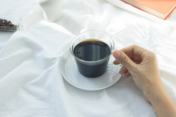 woman's hand holding a glass coffee cup.