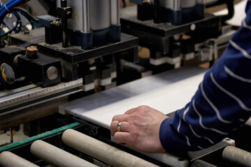 A worker processes furniture blanks on a machine tool in a factory. Industrial production of furniture.