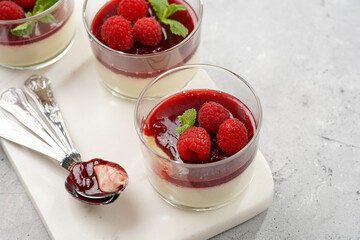 Italian dairy dessert panna cotta with raspberry jam, fresh raspberries and mint on marble board