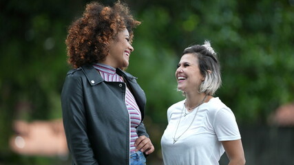 Two happy diverse women standing outside smiling