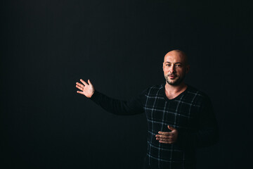 a young man, businesslike, sociable speaker, says something with gestures. in the studio on a black...