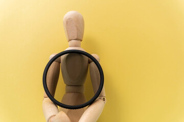 A polarizing filter in the hands of a wooden dummy with space for copying text. Accessory for the photographer