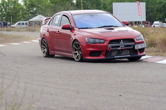 Red sedan drives at high speed on a paved road. Mitsubishi Lance