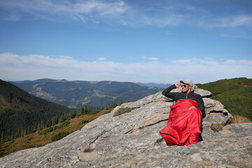 Fototapeta premium Tourist in sleeping bag on mountain peak